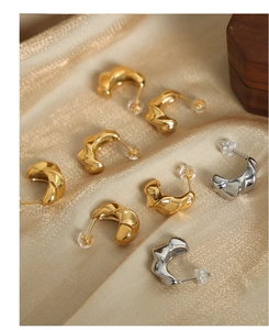Detailed macro view of 18k gold plated twisted C-shape hoop earrings on satin