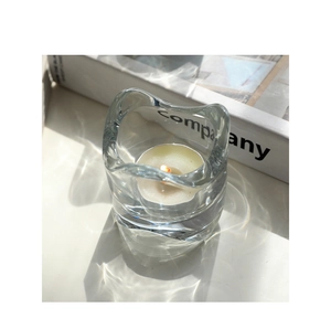 Macro view of transparent glass candle holder with wavy edges and tea light candle