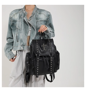 Detail of black leather backpack featuring metallic cross studs and gothic rivet design
