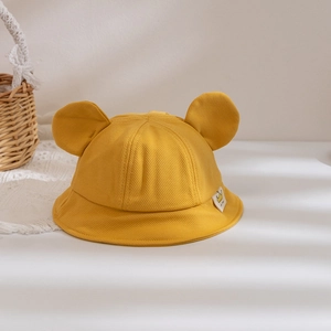 Detail of yellow baby bucket hat with cute bear ears and crown tag on soft fabric