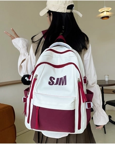 Detail of vintage college backpack featuring cream and burgundy panels with charm
