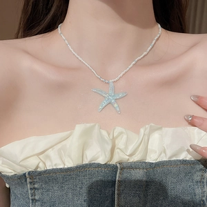 Close-up of beaded necklace with a blue starfish pendant on a model for beach style