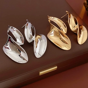 Close-up of gold and silver twisted leaf earrings on dark leather display case
