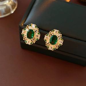 Vue macro de boucles d'oreilles dorées avec pierre ovale verte et zircons blancs