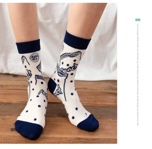 Detail of peach themed mid-calf socks featuring navy blue accents and sweet patterns