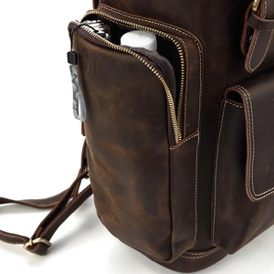 Detail view of the deep brown leather backpack showing a side pocket for water bottles