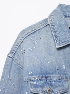 Détail d'une veste en jean bleu clair avec ornements en strass et col effet usé vieilli
