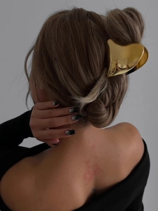 Detail of golden heart-shaped metal hair claw clip securing an elegant bun hairstyle