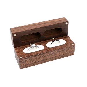 Detail of walnut wood ring box featuring dual slots and soft white lining for two rings