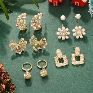 Detailed set of six gold bow and pearl stud earrings displayed in a festive holiday scene