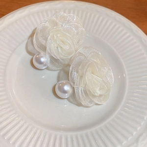 Detail of elegant lace flower earrings with large pearls on a white vintage plate