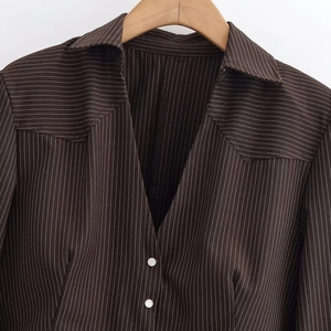 Women's dark brown striped shirt with V-neckline and shoulder pads on a wooden hanger