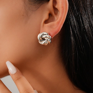 Close-up of a silver-tone knot stud earring worn by a model in a minimalist style
