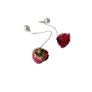 Elegant drop earrings with red rose buds, white pearls and gold chains on a white background