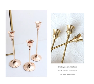 Detail van drie roségouden messing kandelaars met slanke stelen en stabiele kegelvoet