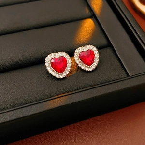 Dettaglio macro di orecchini a cuore vintage con gemme rosse e alone di diamanti