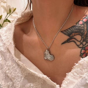 Close-up of 18k silver heart pendant with textured finish on a twisted chain necklace