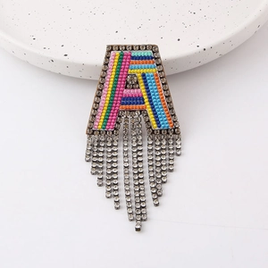 Detailed shot of rainbow embroidered letter A brooch with sparkling rhinestone fringe