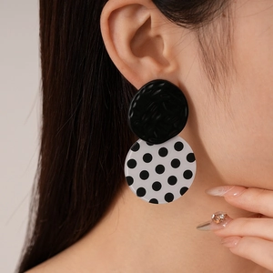 Close-up of vintage black and white polka dot acrylic round earrings on a model