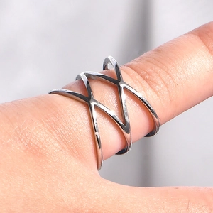 Macro shot of double criss-cross hollow silver stainless steel ring on finger