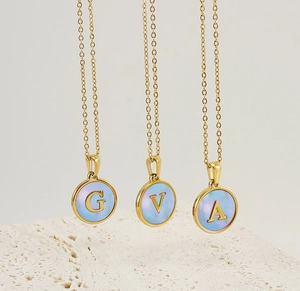 Détail de colliers en or 18 carats avec pendentifs lettres G, V et A en nacre naturelle