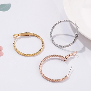 Three pairs of textured hoop earrings in gold, silver and rose gold on a white background