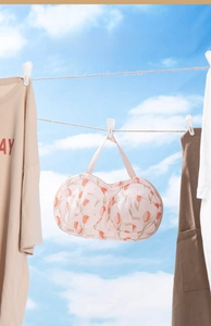 Close-up of mesh bra laundry bag with tulip print hanging against a clear blue sky