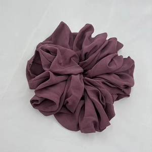 Close-up of deep purple chiffon scrunchie with soft pleated texture on white background