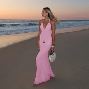 Détail d'une robe longue dos nu rose avec boucle en métal sur une plage au coucher du soleil