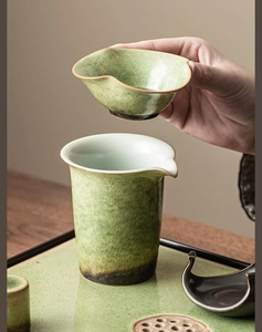 Macro detail of green ceramic tea strainer with kiln-changed glaze on a wooden table
