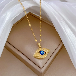 Gold Evil Eye necklace with blue gemstone and white zircon on elegant silk background