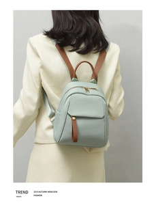 Detail of mint green oxford backpack featuring brown leather straps and gold hardware detail