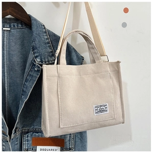 Detail view of beige corduroy tote bag showing woven texture and decorative patch label
