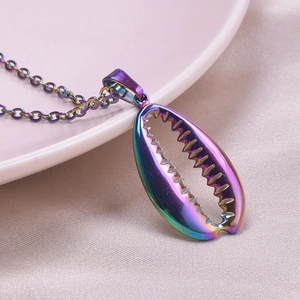 Close-up of rainbow metal cowrie shell pendant necklace on soft pink silk background