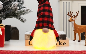 Close-up of a glowing Christmas gnome with red plaid hat and warm white LED beard lights