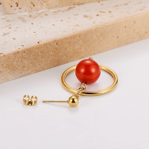 Macro shot of vintage gold hoop earring with red bead pendant and secure backing