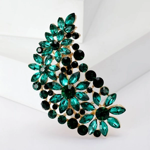 Detail of crescent brooch with emerald and black crystals on gold metal base
