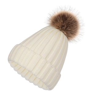 Detailed close-up of white ribbed knit beanie featuring a large fluffy brown faux fur pom
