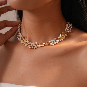 Close-up of elegant gold flower and leaf necklace with white pearls on woman neck