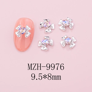 Detailed view of silver alloy bow nail charm with a heart-shaped crystal on pink background