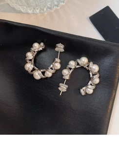 Detail shot of C-shaped silver spiral earrings with white pearls and sparkling zircons
