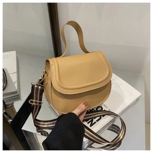 Close-up of beige leather crossbody bag featuring red and green striped shoulder strap