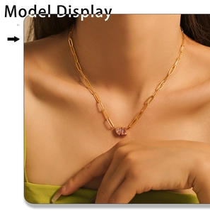 Model wearing gold paperclip link necklace with pink heart and square gemstone pendants