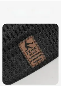 Macro detail of breathable black mesh texture with a sewn brown leather FEWK brand label