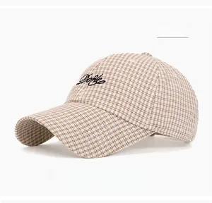 Detail of khaki plaid baseball cap featuring navy blue Dorie embroidery and curved brim
