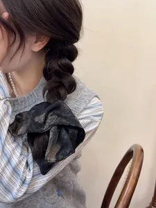 Detail of vintage black floral scrunchie with golden patterns on a braided hairstyle