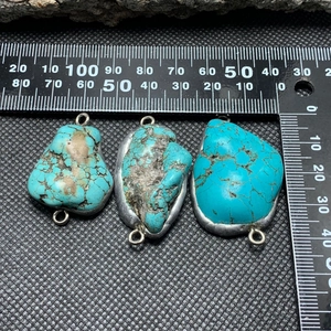 Macro detail of irregular turquoise pendants with silver edges on a measuring scale