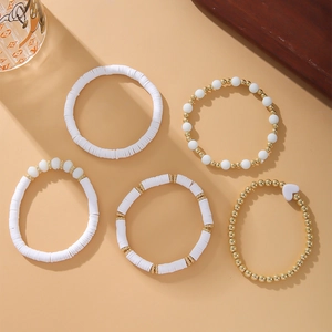 Detail of five-piece Bohemian bracelet set with white Heishi beads and golden heart charm