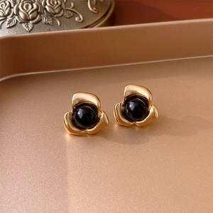 Detailed macro view of vintage golden flower earrings with centered black round beads