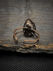 Macro shot of a vintage bronze adjustable ring featuring a raw dark natural gemstone